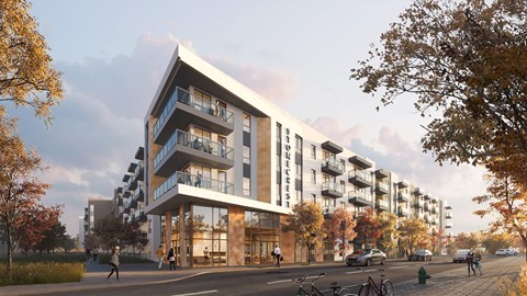 A modern apartment building with a glass facade and balconies is surrounded by trees and people walking on the sidewalk.
