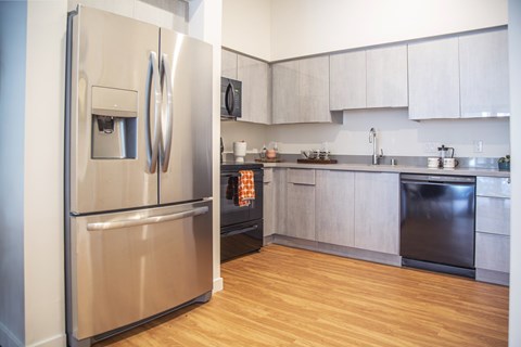 A modern kitchen with a stainless steel refrigerator and wooden floors.