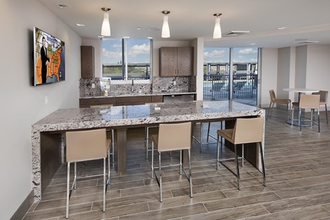 A modern kitchen with a marble island and chairs.