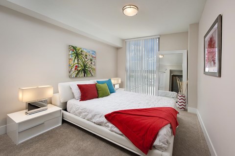 A bedroom with a bed, nightstand, and a painting on the wall.