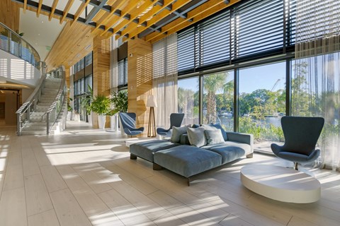 A modern living room with a curved sofa and a glass staircase.