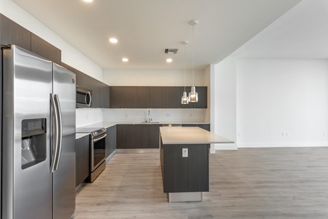 A modern kitchen with a stainless steel refrigerator and wooden cabinets.