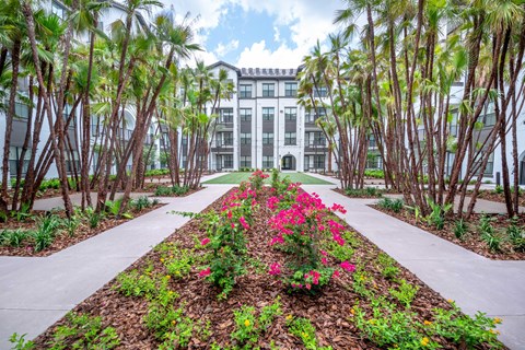 A pathway with a flower bed in the middle leads to a building.