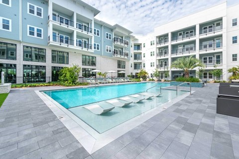 A modern apartment complex with a pool in the foreground.