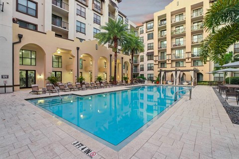 A pool surrounded by buildings and palm trees.