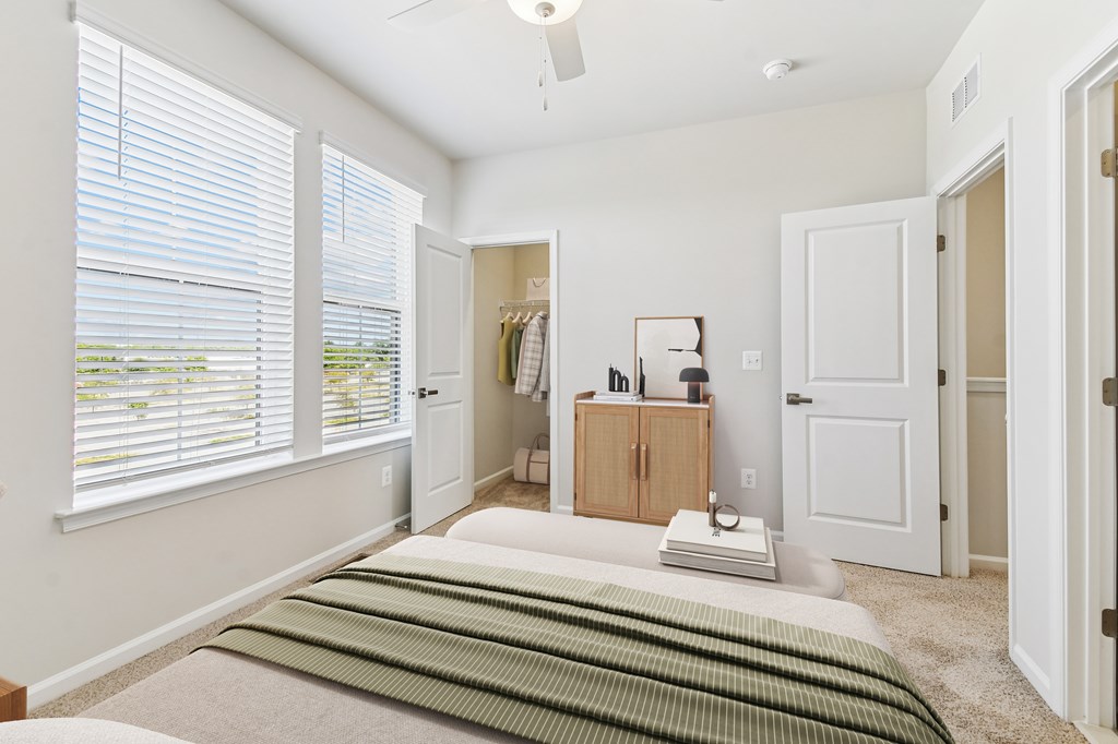 A bedroom with a bed, a window with blinds, a dresser, and a ceiling fan.