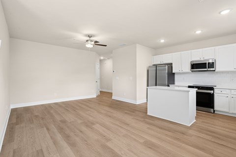 A kitchen with white cabinets and a wooden floor.