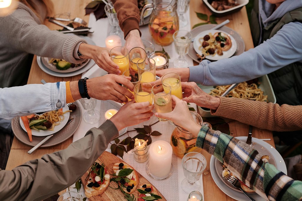 a group of people raising their glasses over a dinner table