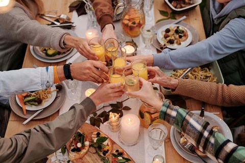 a group of people raising their glasses over a dinner table