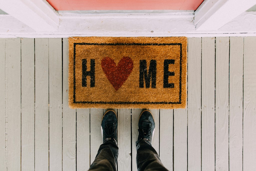 a person standing behind a sign that says home with a heart on it