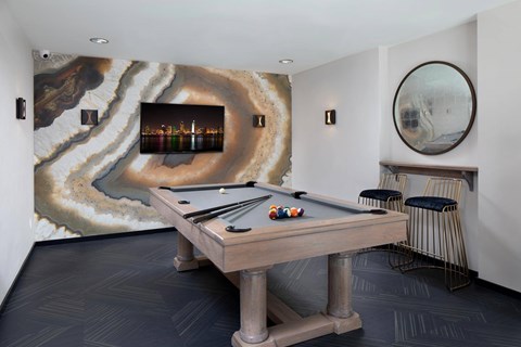 A pool table in a room with a marble patterned wallpaper.