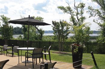 a patio with tables and chairs overlooking a body of water