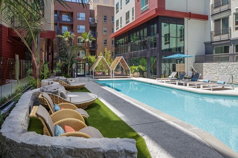 A pool area with lounge chairs and a stone wall.