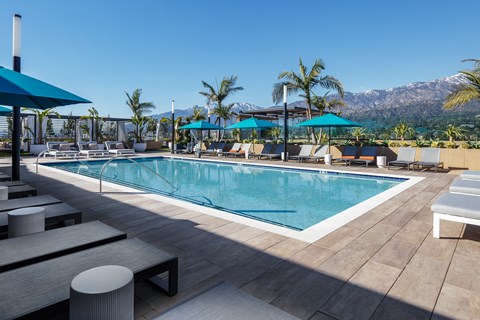 a resort style pool with lounge chairs and umbrellas