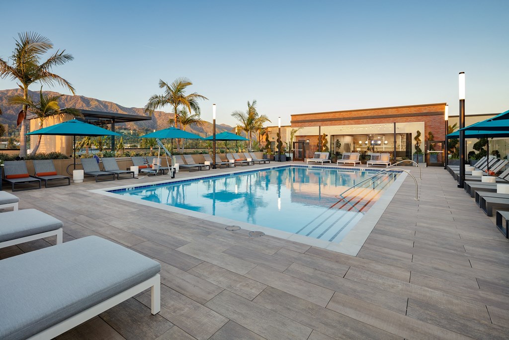 a resort style pool with lounge chairs and umbrellas