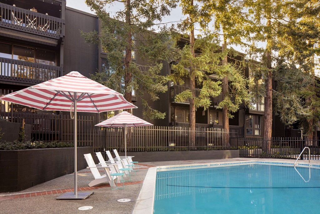 a pool with chairs and an umbrella in front of a building