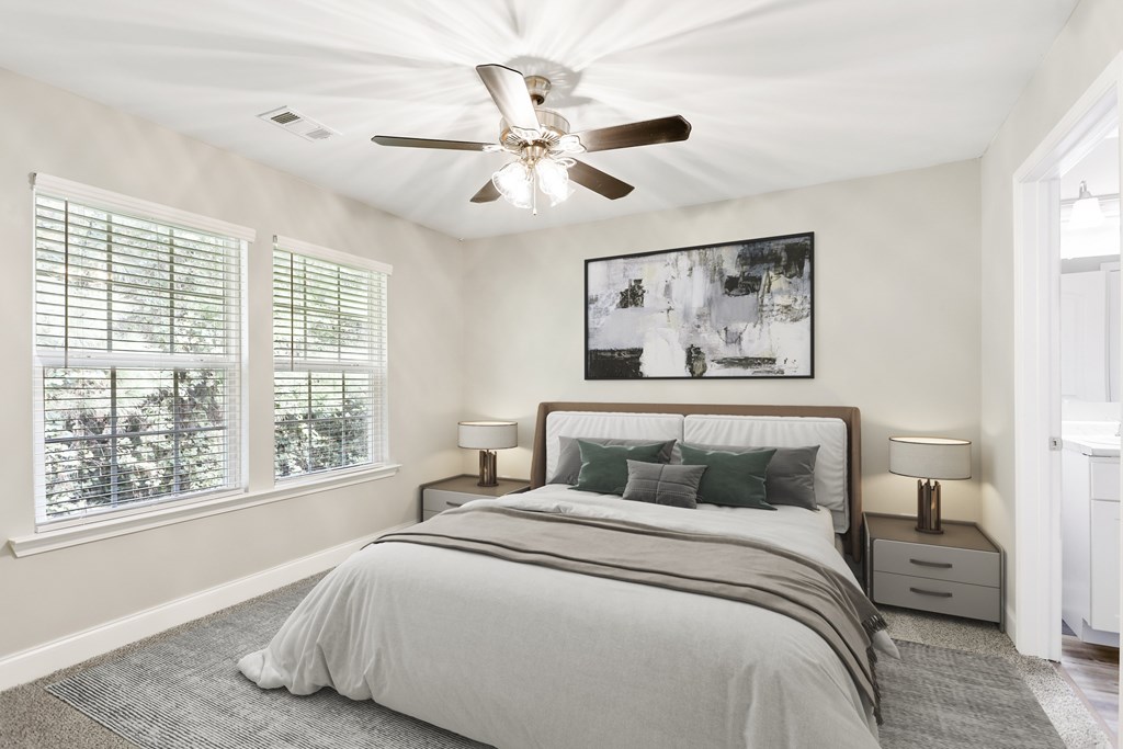 A bedroom with a large bed and ceiling fan at Pooler Station apartments in Pooler, GA.