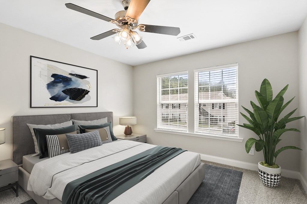 A bedroom with a bed, a ceiling fan, and a potted plant.