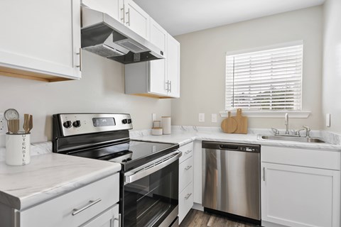 A modern kitchen with white cabinets and stainless steel appliances.