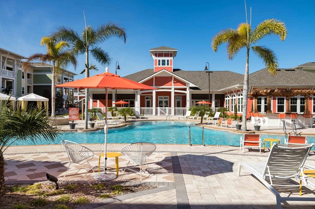 A pool area with a red umbrella and a lifeguard tower.