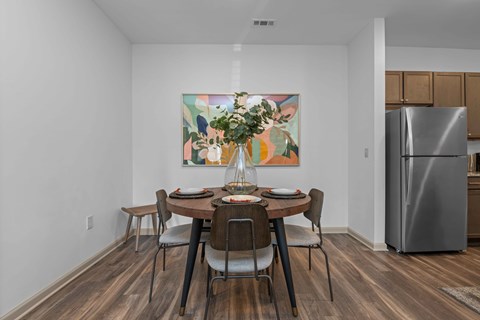 A dining room with a table set for two and a painting on the wall.