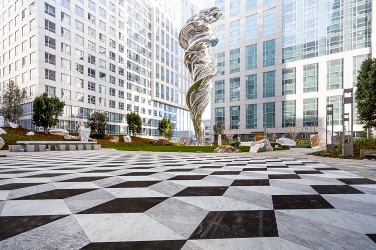 a sculpture in a park in front of a large building