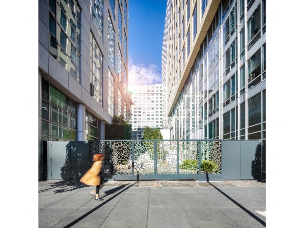 a woman in a yellow dress walking down a sidewalk in front of tall buildings