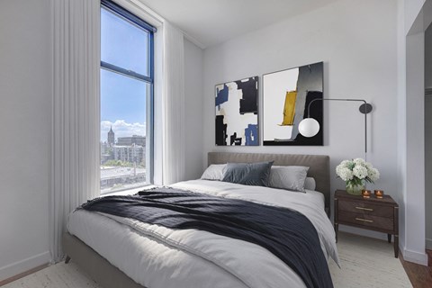 Bedroom with city view, queen sized bed, and decor