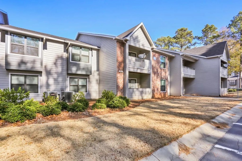 A row of modern apartment buildings with green shrubbery in front.