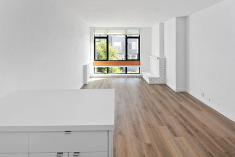 an open living room and kitchen area with white walls and hardwood floors