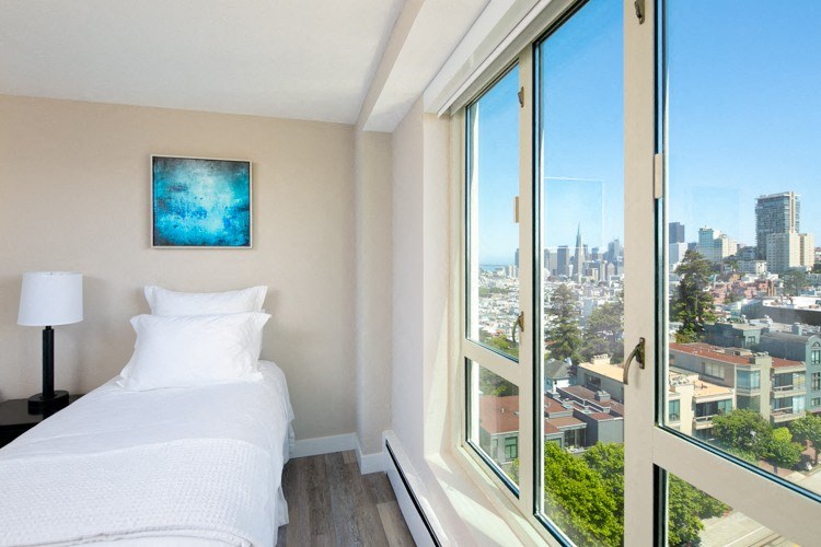 a bedroom with a bed and a large window with a view of the city