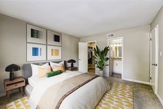 a bedroom with a large bed and a potted plant in a corner of the room