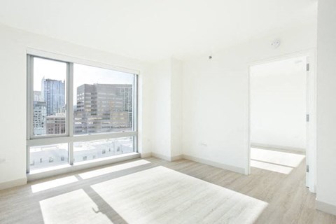 an empty room with a large window and a white rug
