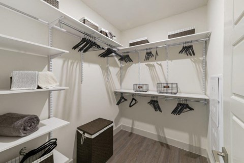 a walk in closet with white walls and shelves