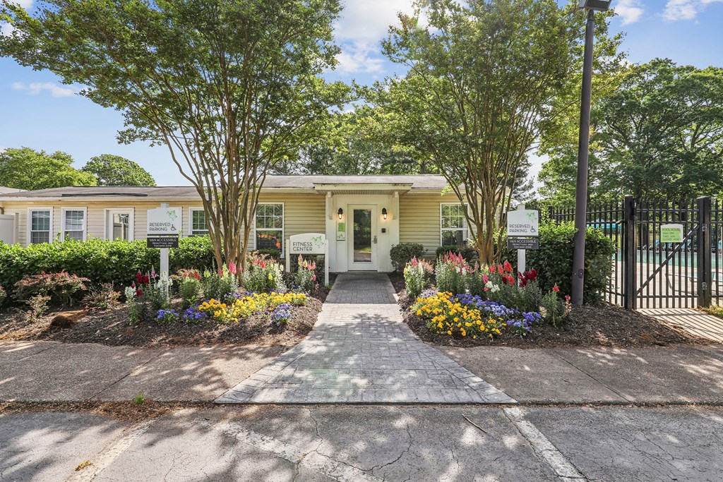 the entrance to a yellow house with a sidewalk and plants and trees