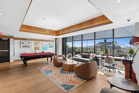 A room with a pool table and a view of the city.