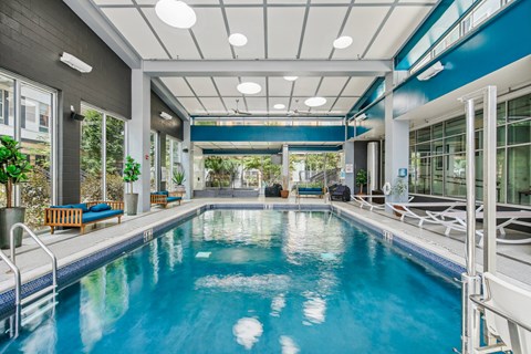A large indoor swimming pool with a blue tinted water.