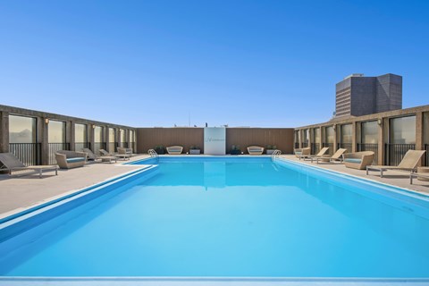 A large swimming pool with lounge chairs and a building in the background.