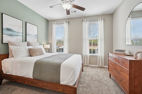 A bedroom with a bed, dresser, and window with curtains.