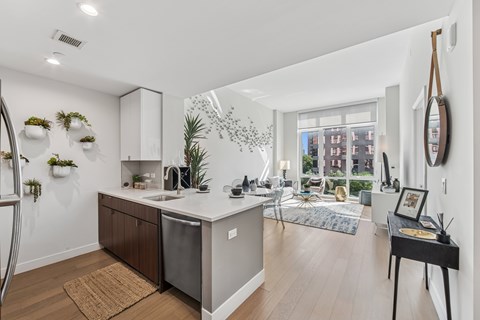 A kitchen with a refrigerator, sink, and a dining table with chairs.