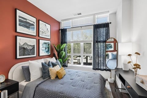A bedroom with a bed, nightstand, and a window with blinds.