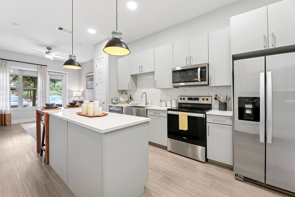 A modern kitchen with a white island and stainless steel appliances.