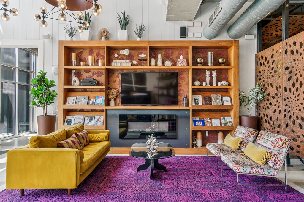A living room with a yellow couch and a purple rug.