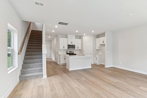 A spacious kitchen and living room with wooden floors and white walls.