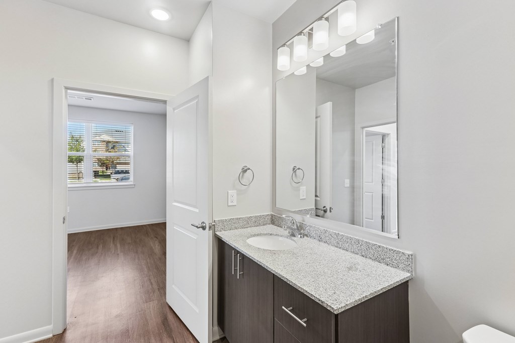 A bathroom with a sink, mirror, and a window.