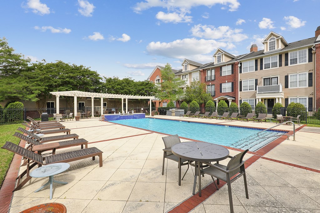 an outdoor pool with tables and chairs next to an apartment building