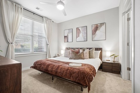 A bedroom with a bed, nightstand, and a window with curtains.