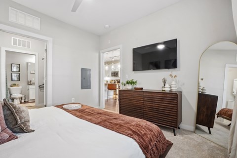 A bedroom with a large bed and a flat screen TV mounted on the wall.