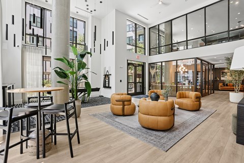 A modern living room with a glass wall and a large window.