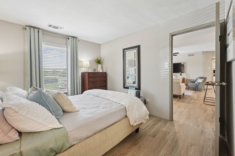 A bedroom with a large bed and a window with curtains.